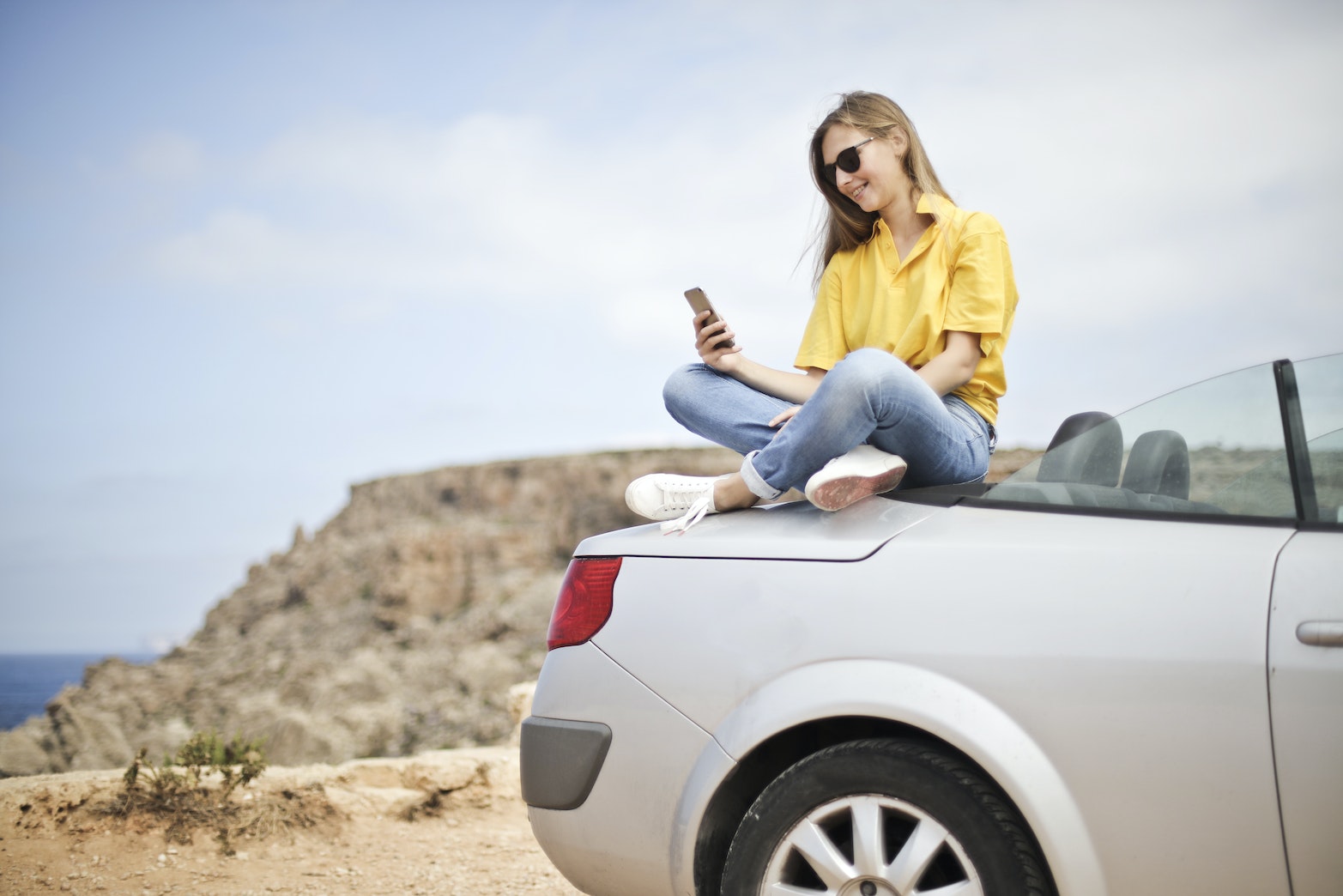Vrouw in gele blouse op auto zittend online afspraken Huisarts Javea